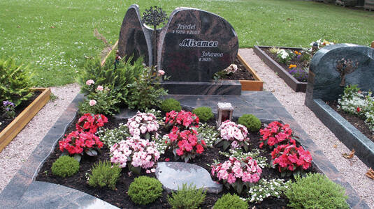 Gedenkstätte in dunkelrotem und grauen Granit mit Bronzeplastik "Lebensbaum".