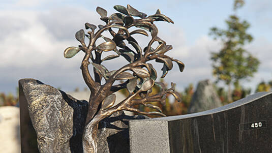 Dunkler Granit mit Bronzeskulptur 'Lebensbaum'.